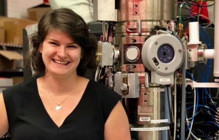 Berit Goodge standing in front of an electron microscope.